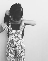 Girl wearing floral pattern jumpsuit standing against wall
