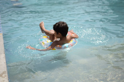 Happy indian boy swimming in a pool, kid wearing swimming costume along with air tube