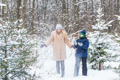 Woman standing by tree in forest during winter