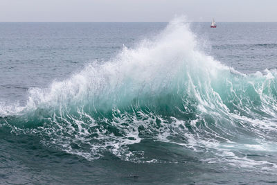 Waves splashing on shore against sky