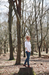 Smiling young woman standing on tree stump