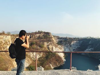 Man photographing on mountain against sky