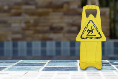 Close-up of yellow sign on swimming pool