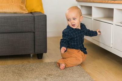 Portrait of cute boy sitting on hardwood floor at home