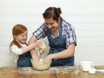 Two girls baking cake in kitchen
