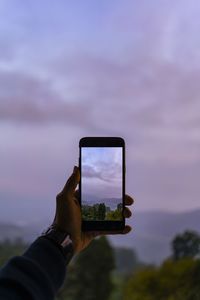 Low section of person using mobile phone against sky