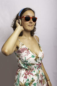 Woman wearing sunglasses standing against gray background