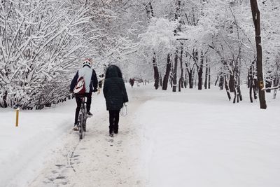 Rear view of people walking on snow during winter