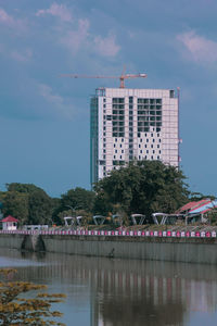 Buildings by river against sky