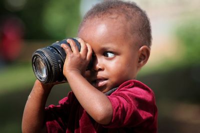 Close-up of boy looking through camera lens