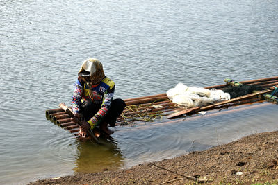 High angle view of fisherman sailing wooden raft in river