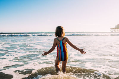 Behind shot of young girl running into ocean