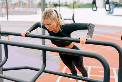 Young athletic woman doing push-ups exercising on the sports ground.