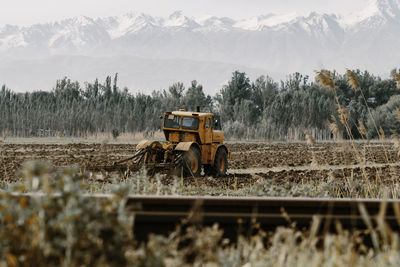 Orange color tractor working on the field. toned