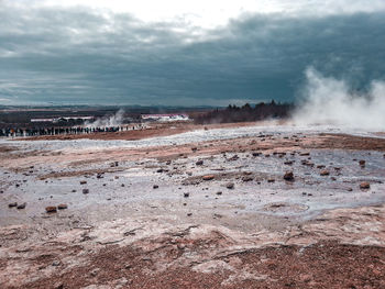 Geysir and tourists under cloudy sky