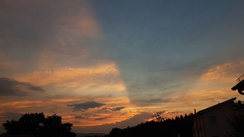 Low angle view of silhouette trees and buildings against sky during sunset