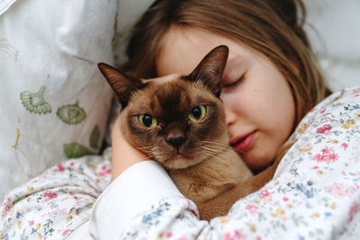 Close-up of sleeping girl with burmese cat