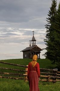 Rear view of woman standing on field against sky