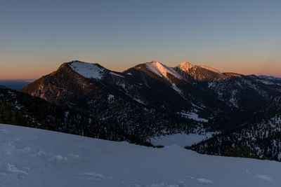 Scenic view of snowcapped mountains against clear sky during sunset