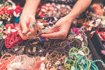 Cropped hands of woman holding jewelry at store