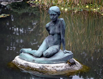 Turtle on female statue in lake