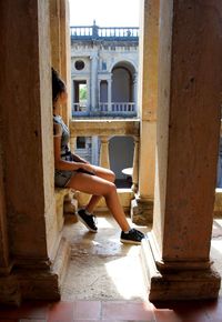 Woman sitting by railing in historic building