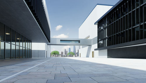 Empty footpath amidst buildings against sky