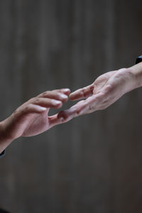 Cropped image of couple holding hands against wall