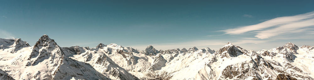 Panoramic view of winter snowy mountains in caucasus region in russia with blue sky