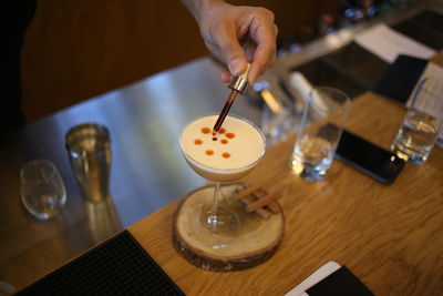 Cropped hand of woman with drinks on table