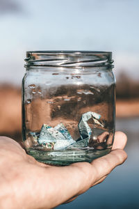 Cropped hand holding jar with origami