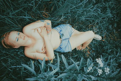 Shirtless woman lying on field