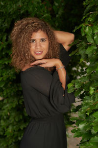 Portrait of smiling young woman standing against plants