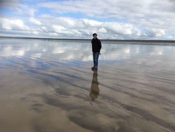 Rear view of man standing on beach against sky