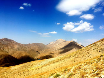 Scenic view of hills against blue sky