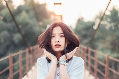 Portrait of beautiful young woman standing against railing