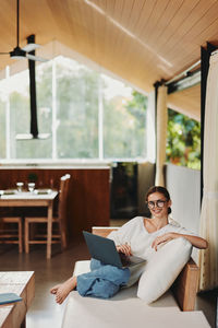 Young woman using mobile phone while sitting on table