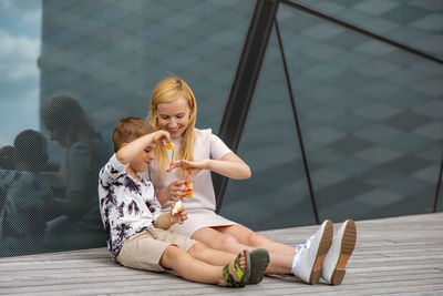 Happy blond woman and little boy sitting on terrace and eating sweets. mother and son 