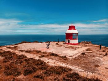 Lighthouse on beach against sky