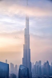 Modern buildings in city against sky during sunset