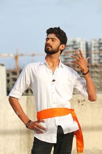 Young man looking away while standing against sky