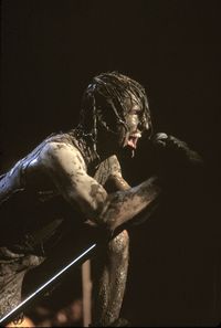 Full length of shirtless man sitting against black background