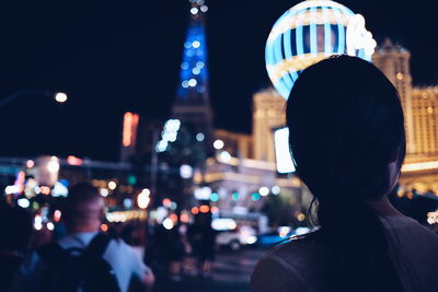 Rear view of man on illuminated city at night