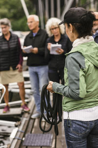 Female instructor holding rope while teaching senior men and women during boat master course