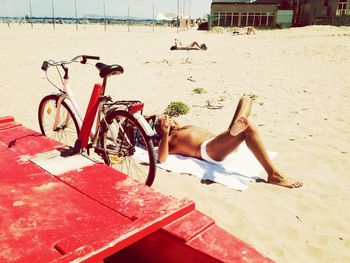 Low section of man lying on beach against sky