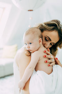 Mother carrying shirtless son at home