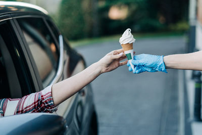 Hand holding ice cream cone against blurred background