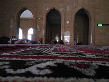 People relaxing on rug at mosque
