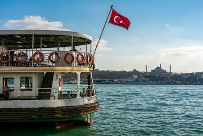 Flag by boat in river against sky