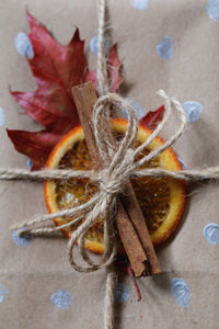 Close-up of cinnamon and citrus fruit tied with threads on paper